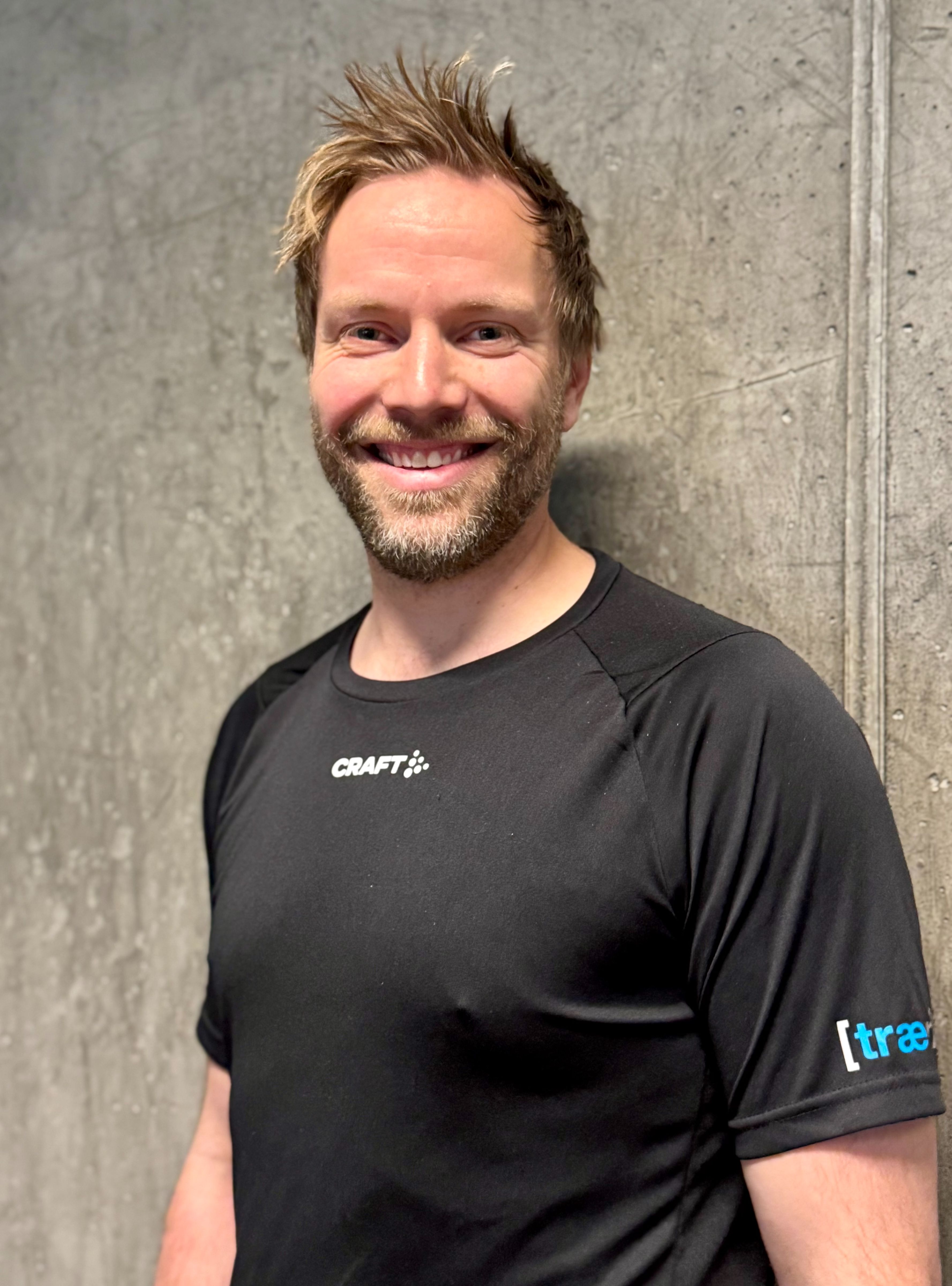 Kvinne sitter på gulvet ved kettlebell og vannflaske i treningsstudio.