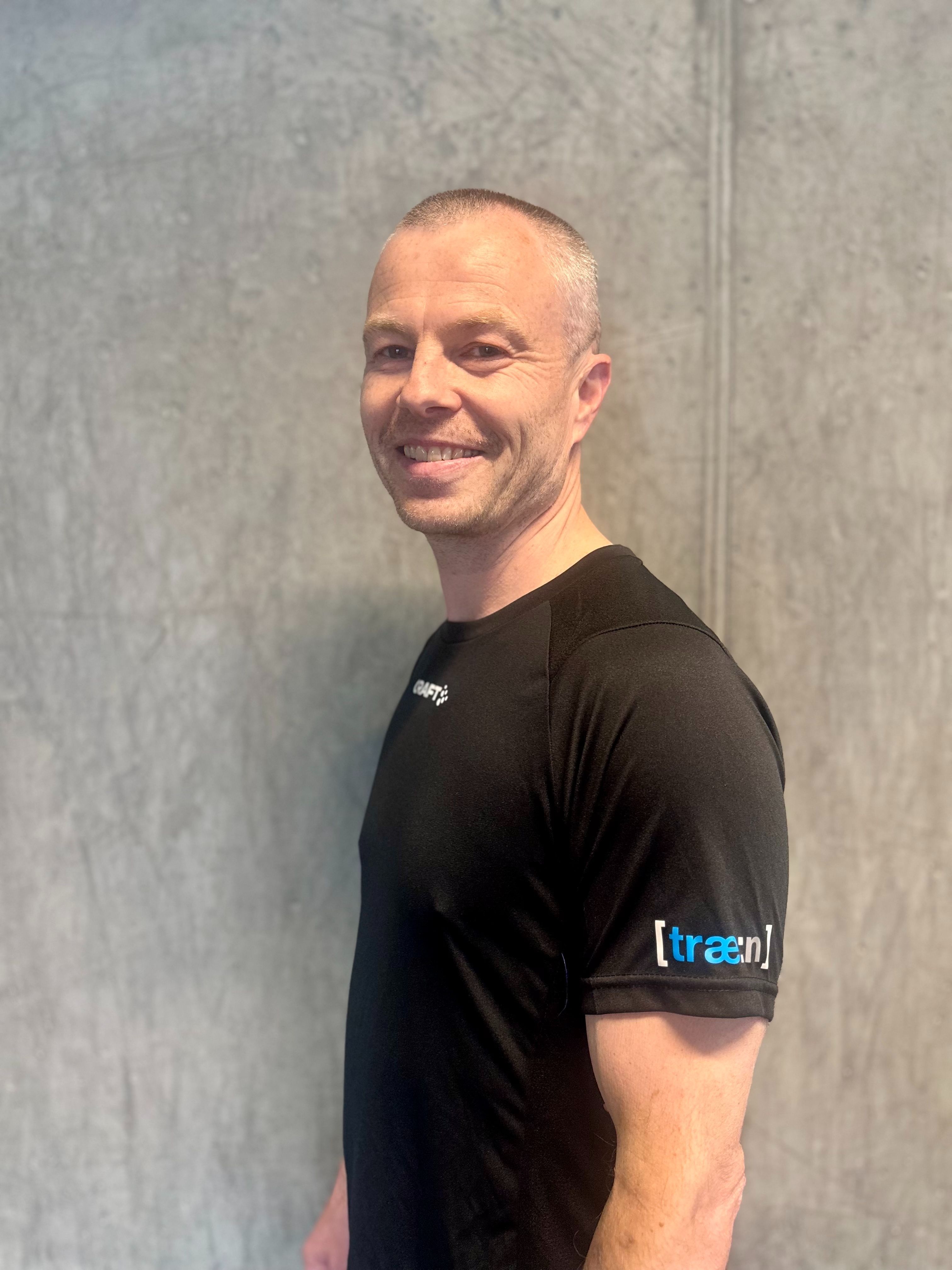 Kvinne sitter på gulvet ved kettlebell og vannflaske i treningsstudio.