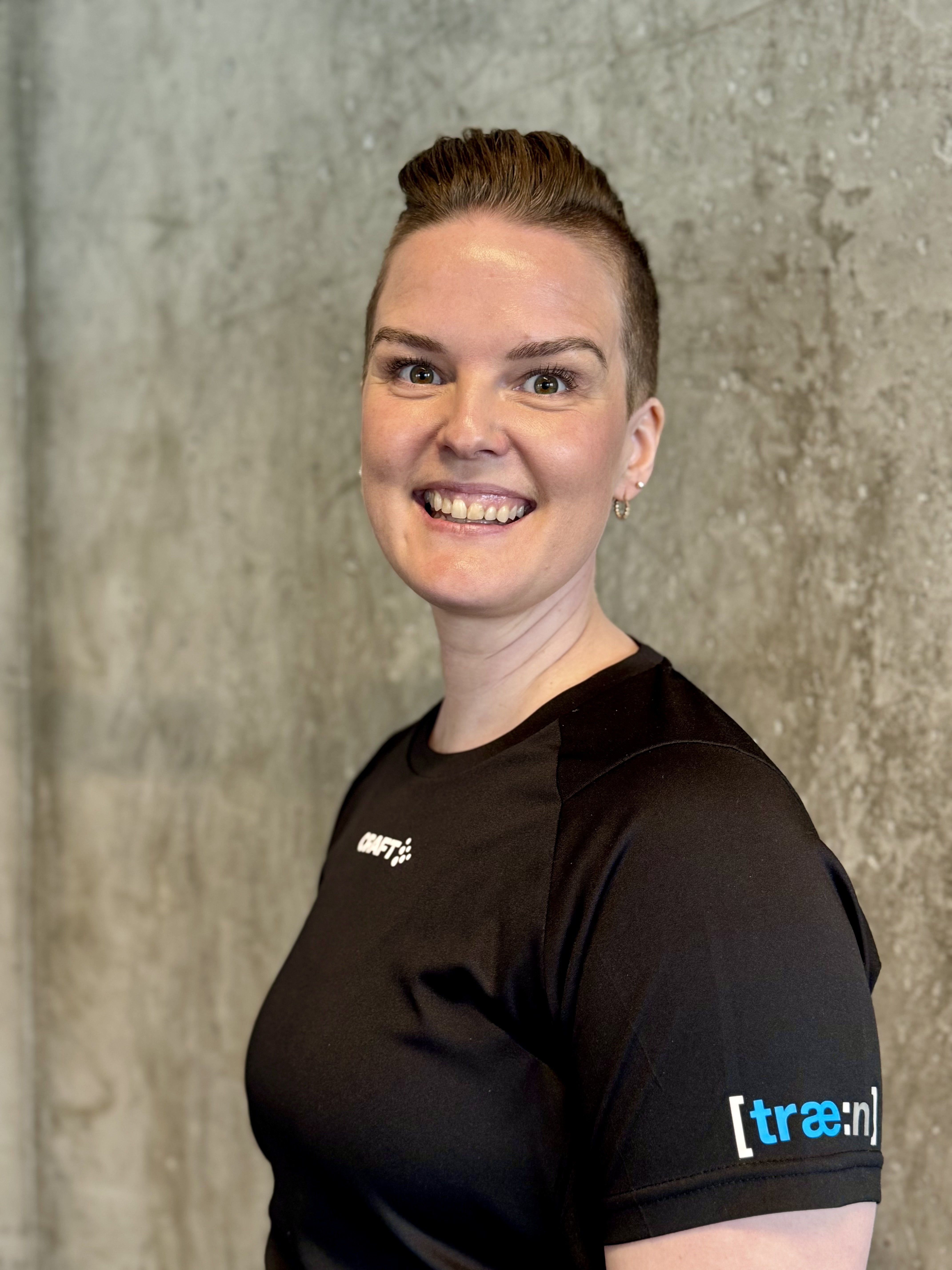 Kvinne sitter på gulvet ved kettlebell og vannflaske i treningsstudio.