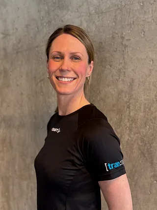 Kvinne sitter på gulvet ved kettlebell og vannflaske i treningsstudio.